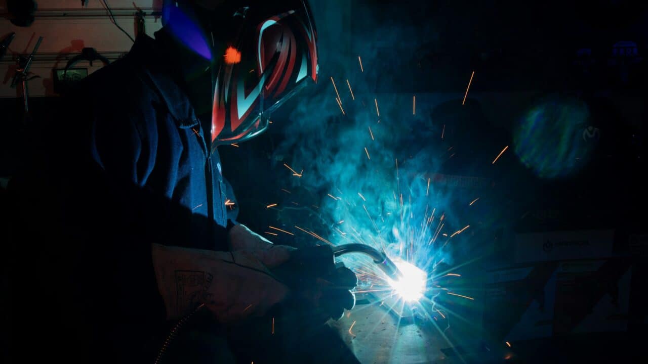 A welder working with bright sparks in a dark environment